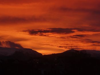 Scenic view of silhouette mountains against orange sky