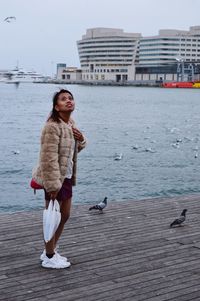 Woman looking away while standing at riverbank in city