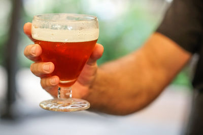 Human hand holding a glass full of red beer