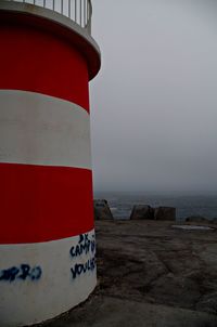 Lighthouse by sea against clear sky