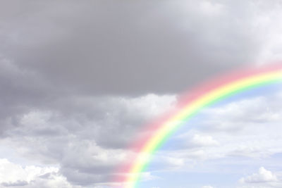 Low angle view of rainbow against cloudy sky