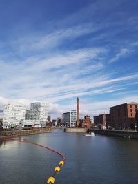 River by buildings against blue sky