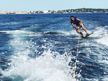 Young man kiteboarding on sea against sky