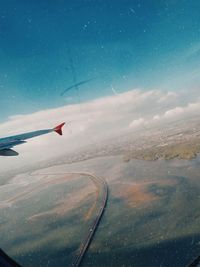 Airplane flying in sky seen through glass window