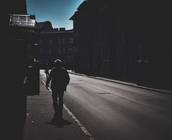 Rear view of a man walking on road