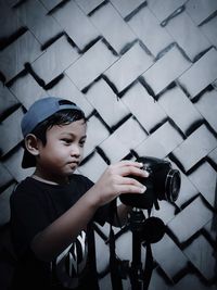 Full length of boy photographing against wall