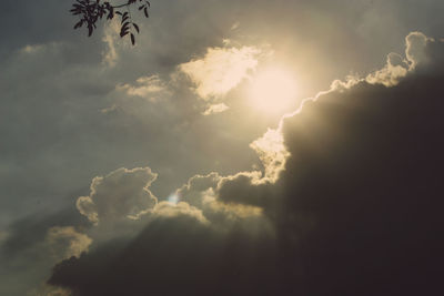 Low angle view of sunlight streaming through clouds