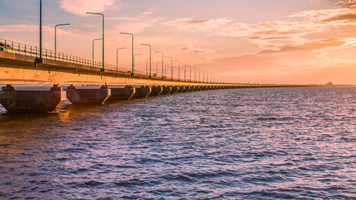 Bridge over sea against sky during sunset