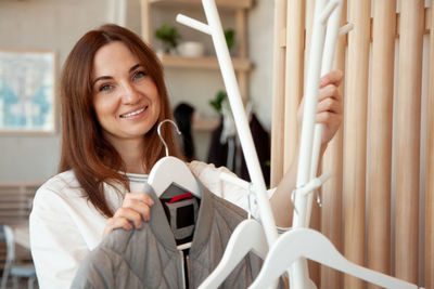 Portrait of smiling young woman holding camera at home