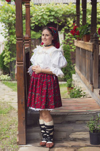 Portrait of happy young woman in romanian clothing standing on porch