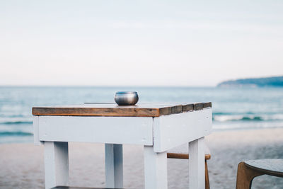 Container on table at beach against sky