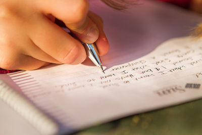High angle view of woman writing on book