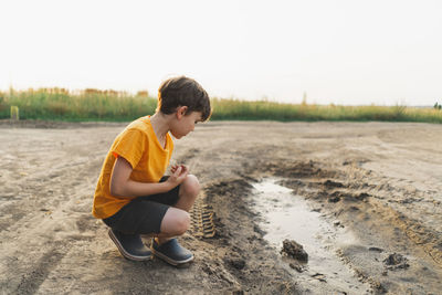 Side view of boy sitting on field