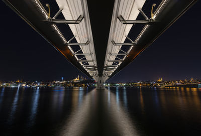 Illuminated bridge over river at night