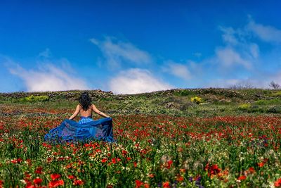 Woman with pink flowers on field against sky