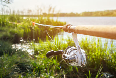 Close-up of fishing rod on grass by lake