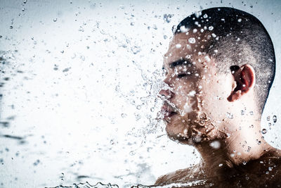 Close-up portrait of young man splashing water