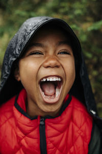 Excited boy screaming wearing raincoat in forest