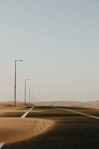 Road amidst field against clear sky