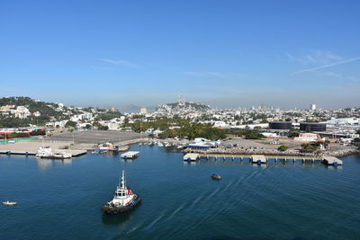 High angle view of buildings by sea against blue sky