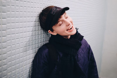 Smiling young woman standing against wall