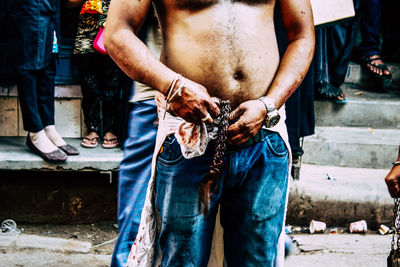 Midsection of man holding camera while standing on street