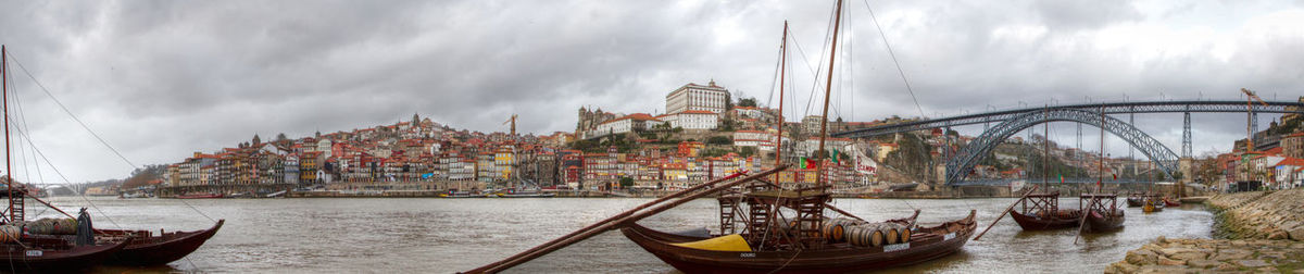 Boats in river against cloudy sky