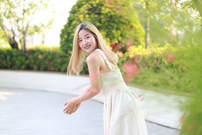 Portrait of young woman standing against trees