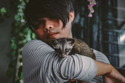 Close-up of young man holding meerkat