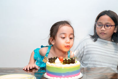 Little girl is blowing candles on her birthday cake. celebrating at home during quarantine.