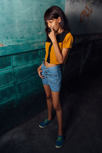 Young woman standing against wall