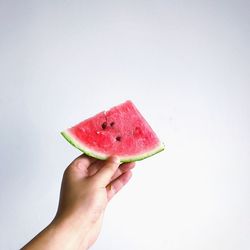 Close-up of hand holding apple against white background