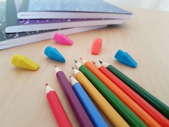 High angle view of colored pencils by erasers and books on table