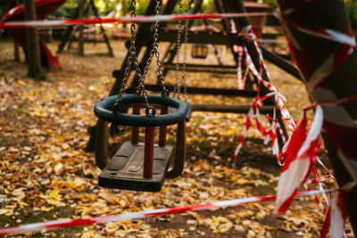 Empty wooden swing on playground fenced with red and white attention tape during coronavirus pandemic