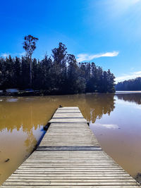 Pier over lake against blue sky