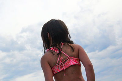 Rear view of woman in bikini standing against sky