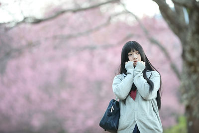 Woman standing by pink flower tree