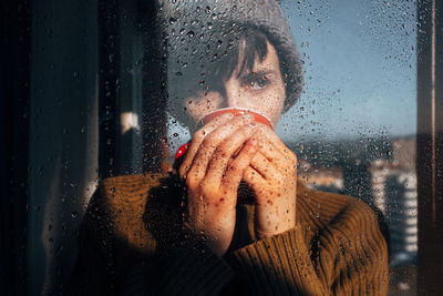 Portrait of woman seen through wet window in rainy season