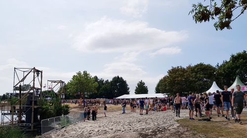 Group of people playing soccer against sky