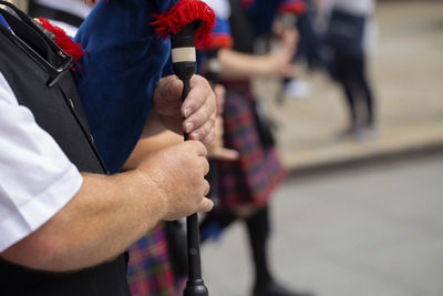 Midsection of musician playing bagpipe on street in city