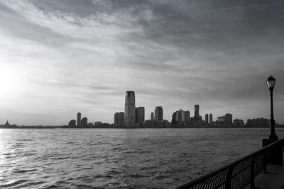 City at waterfront against cloudy sky