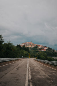 Road by trees against sky