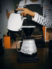 Cropped hand of woman holding coffee on table