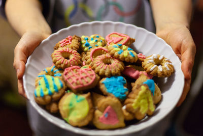 Close-up of hand holding a plate full of colorful homemade biscuits 