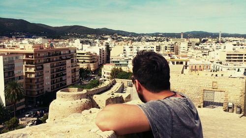 Man standing by building in city on sunny day