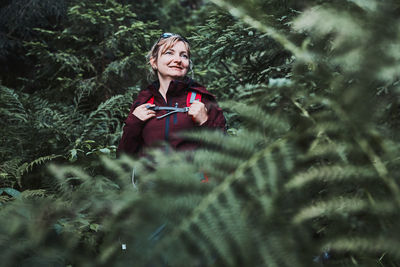 Woman with backpack hiking in forest, actively spending summer vacation close to nature