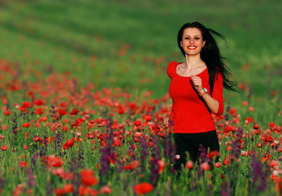 Portrait of smiling young woman standing against red plants