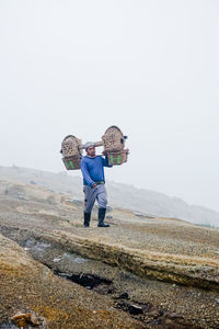 Full length of man carrying wicker baskets on land outdoors