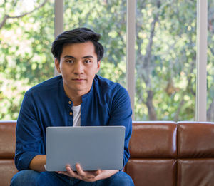 Young man using mobile phone while sitting on sofa