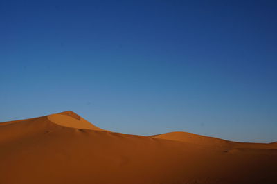 Scenic view of desert against clear blue sky